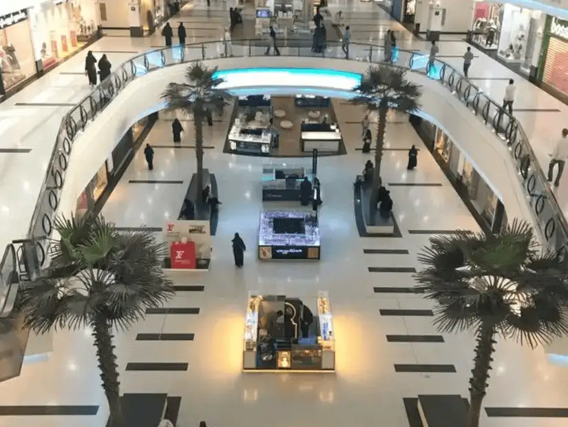 Interior view of Riyadh Gallery Mall with palm trees and kiosks.