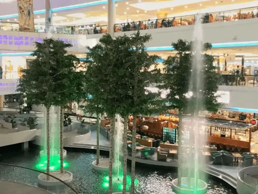 Vibrant, illuminated fountain area with seating inside Riyadh Gallery Mall.