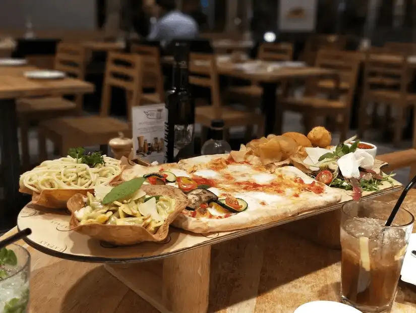 Fresh bruschetta and a mixed green salad on a wooden board.