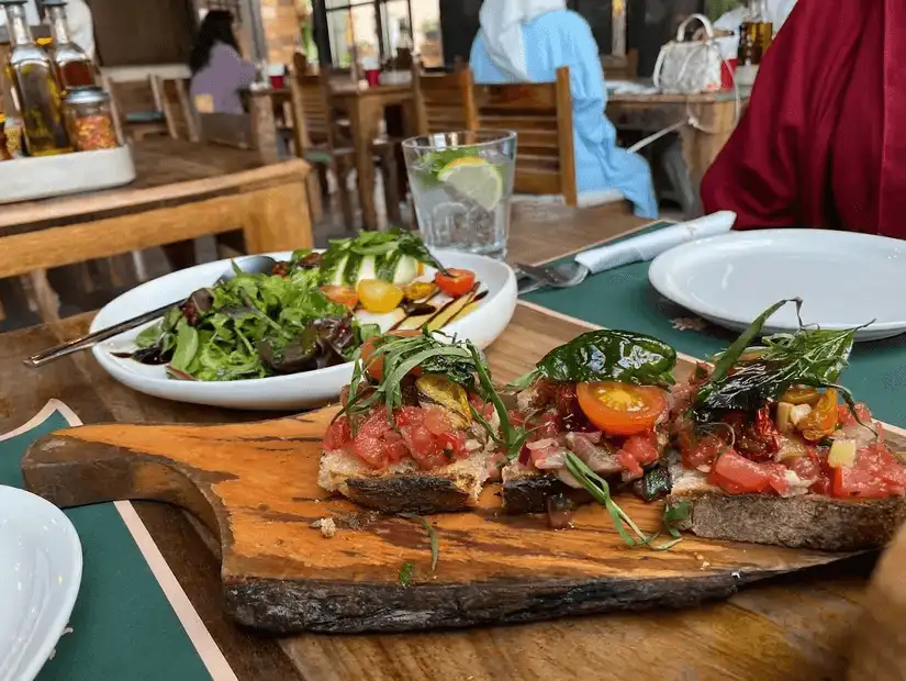 Italian platter with pizza, pasta, and salads on a rustic board.