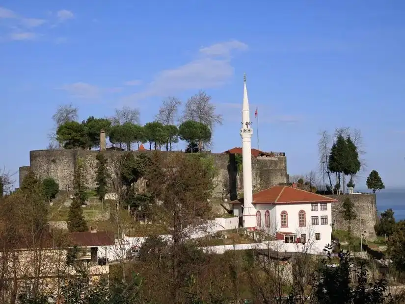 A peaceful riverside image of Rize, with green hills and a calm atmosphere.