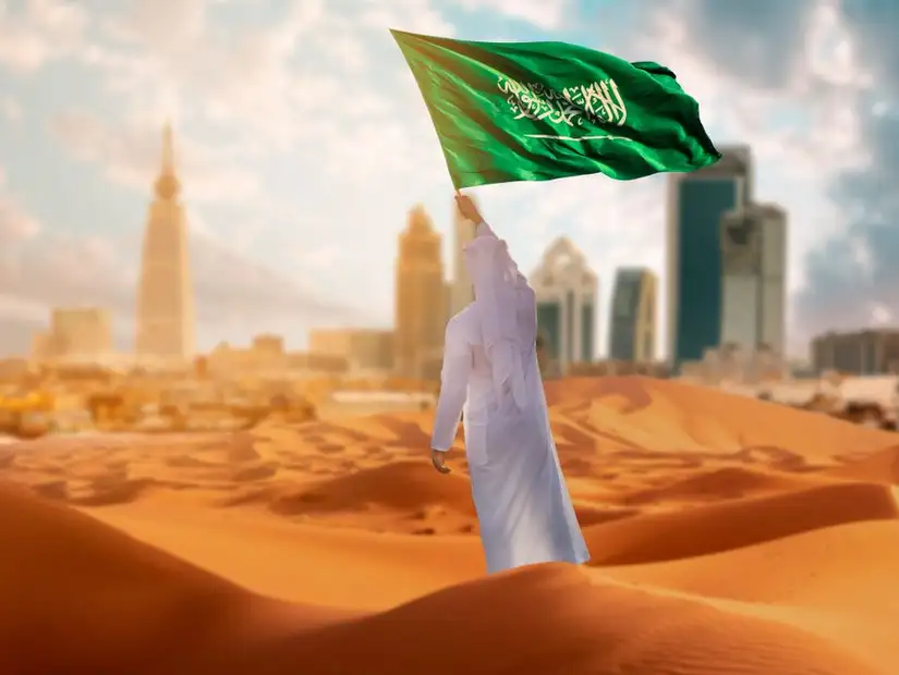 رجل يرفع العلم السعودي في اليوم الوطني