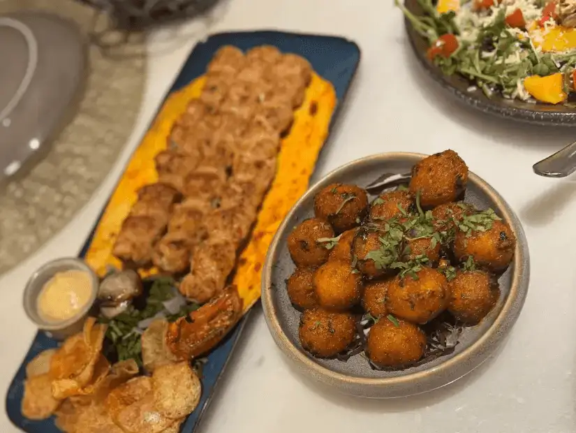 A tasty platter of skewered grilled meat served with a side of crispy potatoes and fresh vegetables.