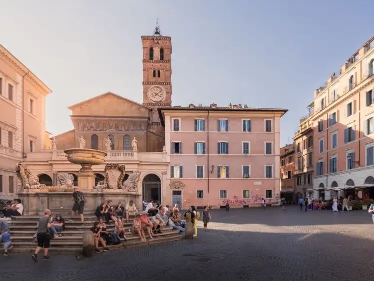 A charming square in Rome with a fountain, lively groups of people, and historic buildings surrounding it.