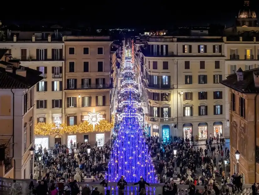 A beautifully decorated street in Rome during Christmas, lit up with colorful lights.