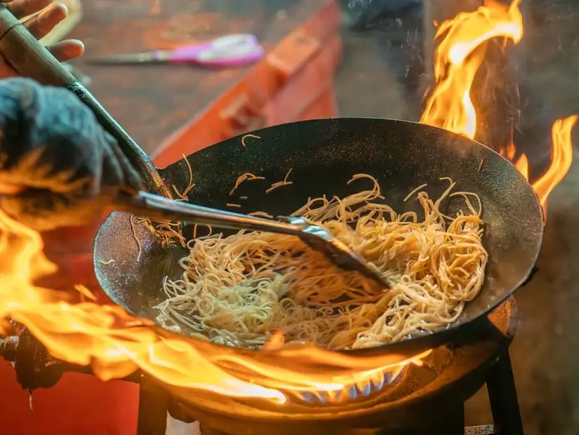 Stir-frying noodles over an open flame