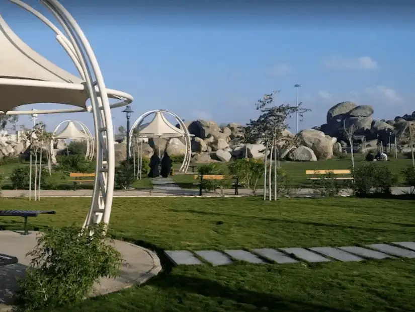 Modern park with shaded seating areas and rocky landscape.