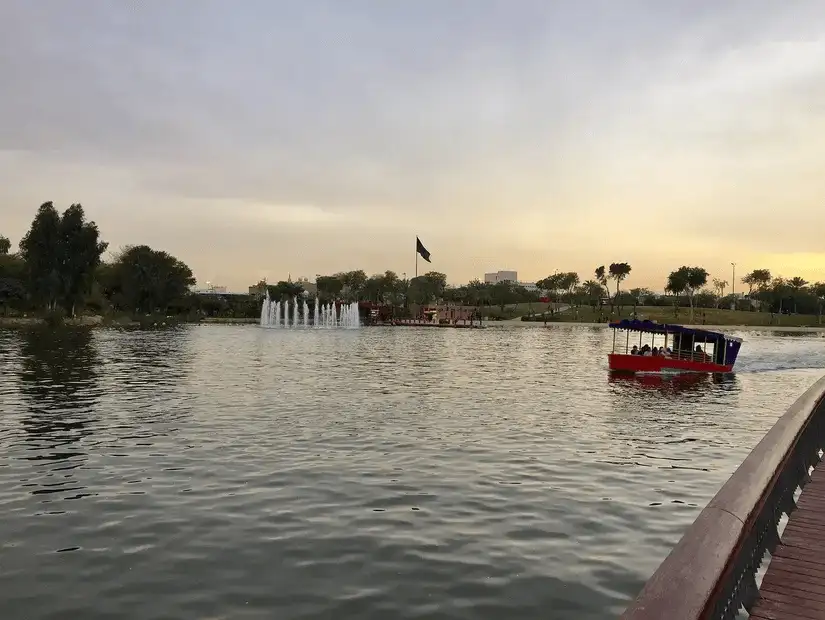 A boat on the lake during a calm evening, with fountains in the distance.