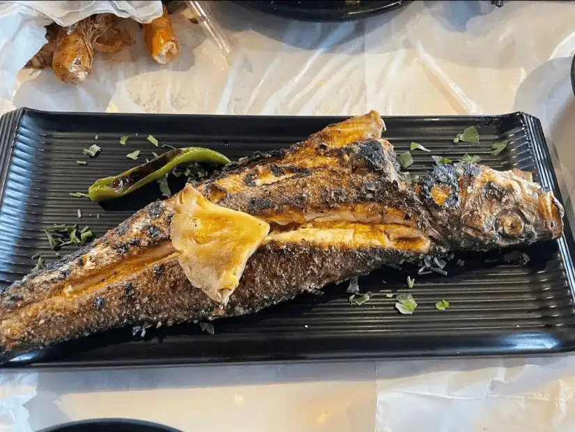 Crispy grilled fish with a tangy lemon wedge.