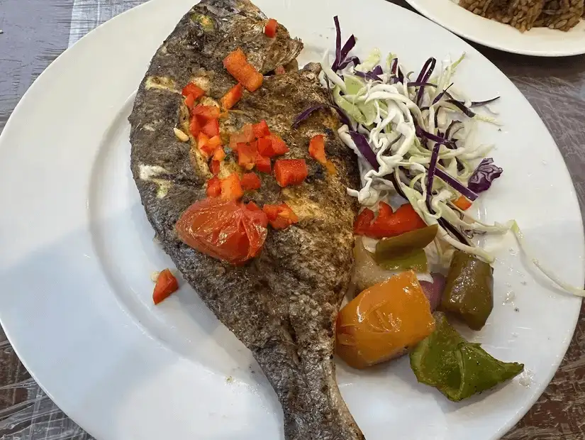 Grilled whole fish with roasted vegetables and salad.