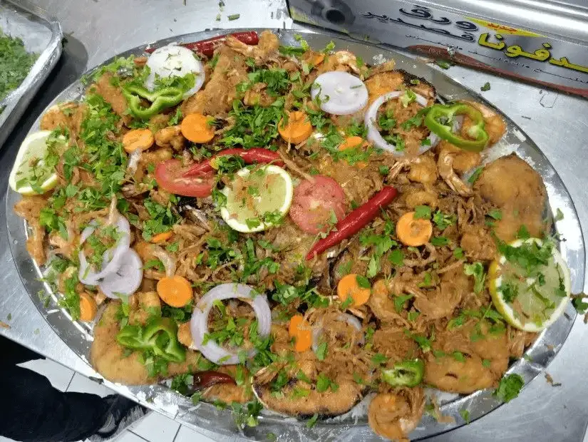 Mixed seafood garnished with fresh herbs and lemon slices.