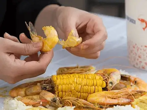 Enjoying a shrimp boil with corn on the cob, a casual yet delicious meal.