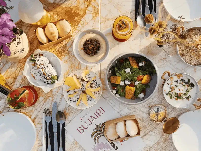 A table set for a luxurious meal at Somewhere Bujairi, complete with fresh salads, appetizers, and refreshing drinks.