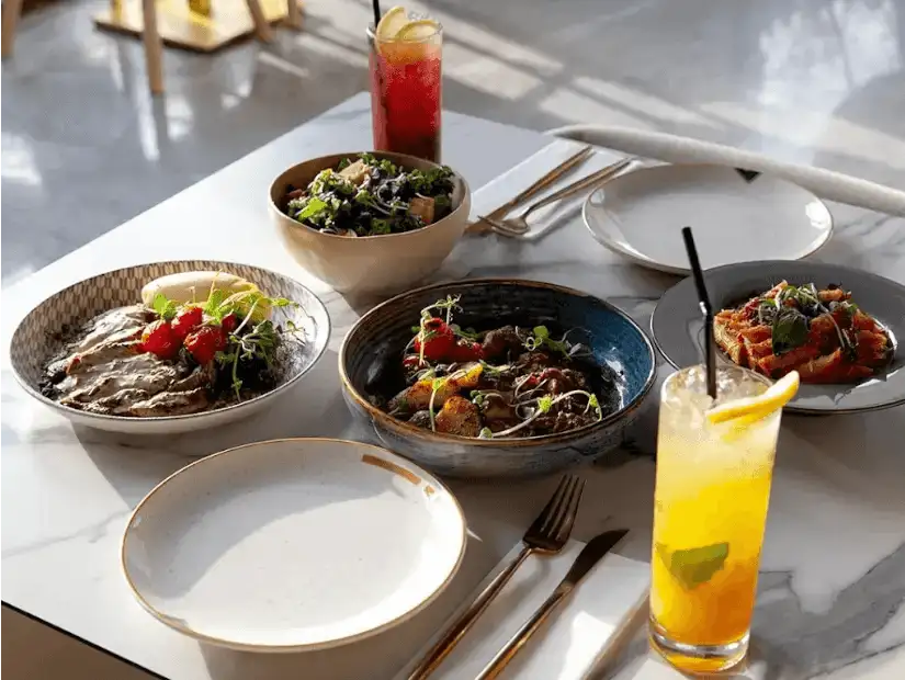 An image featuring two bowls of fresh salad with beverages.