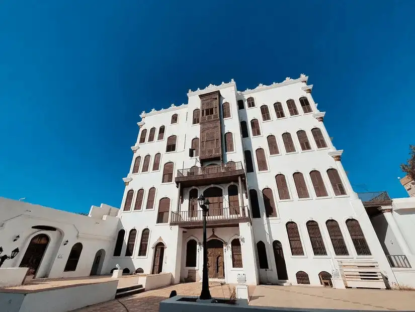 A grand old building with intricate wooden windows against a clear blue sky.