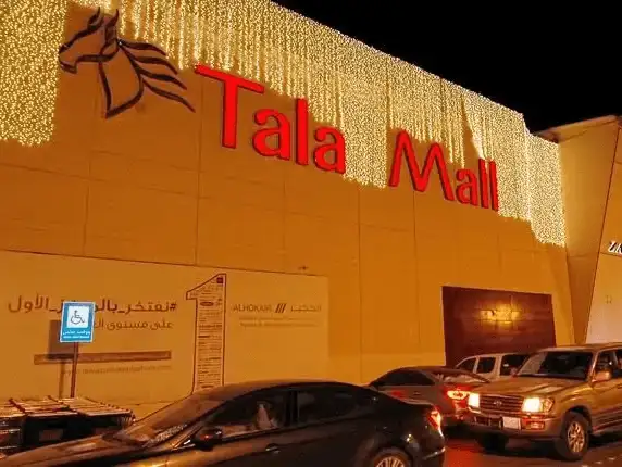 Tala Mall illuminated at night, with vehicles parked outside.