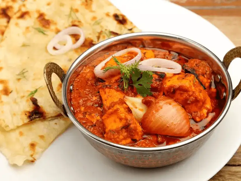 Indian curry feast served in traditional metal dishes with rice and naan.