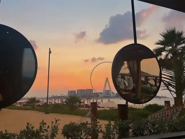 Scenic beachside view with a Ferris wheel and a beautiful sunset.