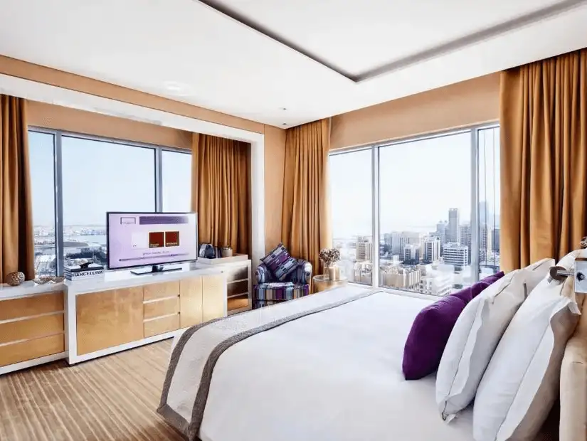 A bright and modern bedroom at The Domain Hotel, overlooking the stunning cityscape of Bahrain.