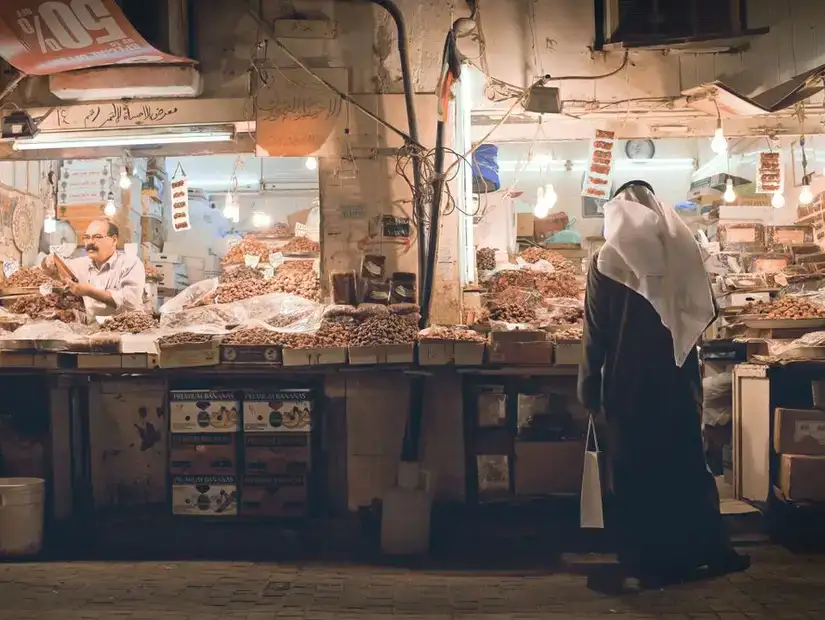 A shopper browsing the traditional souq at Al-Mubarakiya Market, famous for its spices and local products.