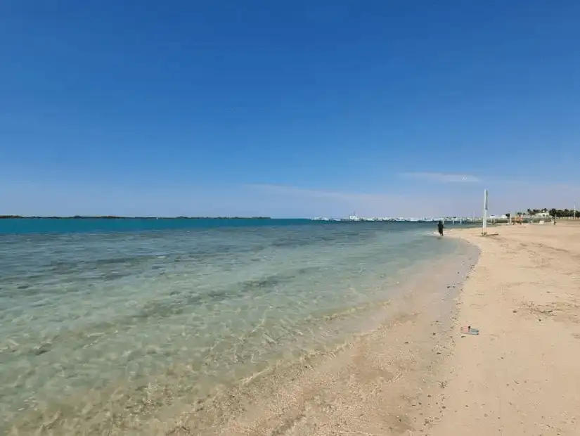 A wide sandy beach with crystal clear waters gently lapping the shore, perfect for a peaceful seaside stroll.