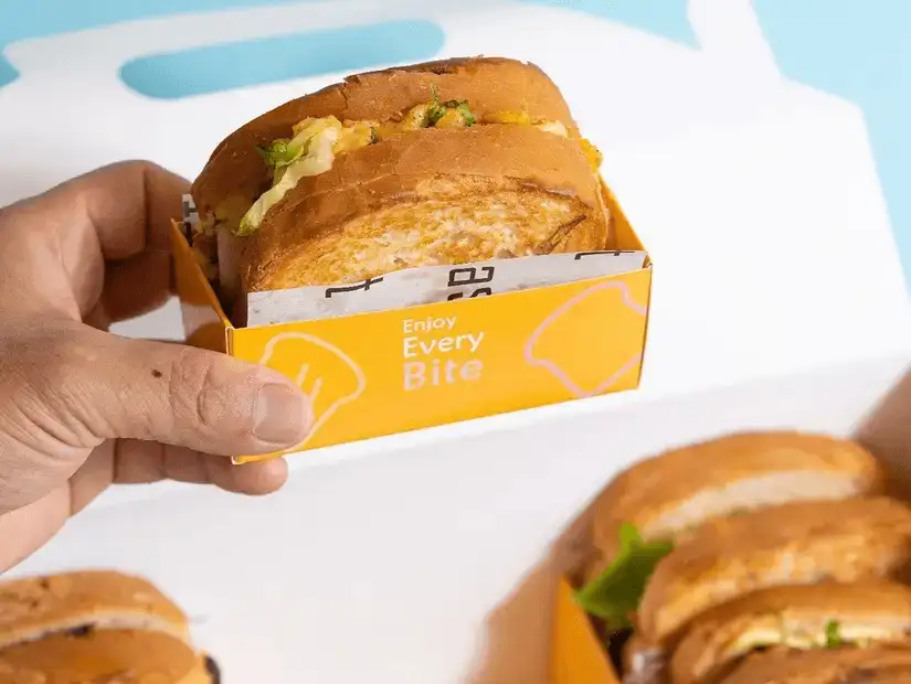 A tasty sandwich in a bright, cheerful box, inviting you to enjoy every bite.