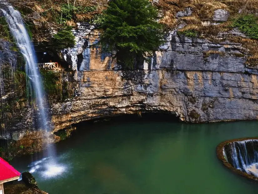 A stunning waterfall cascading into a tranquil pool, surrounded by rocky cliffs.