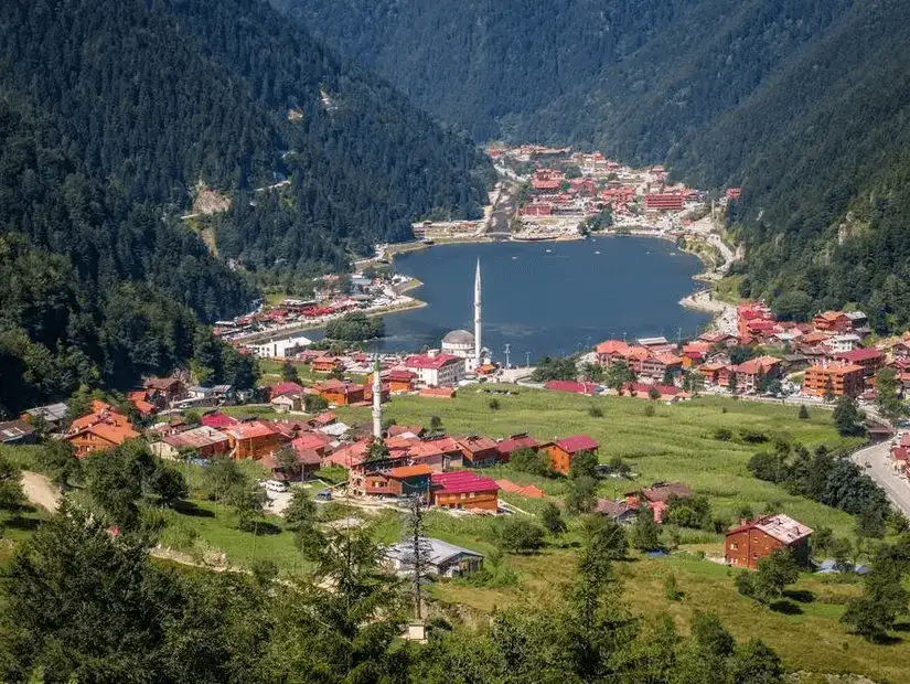 The serene Uzungöl Lake surrounded by a charming village and towering mountains.