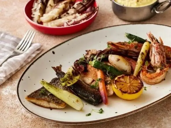 Perfectly grilled seafood and vegetables, served with a side of mashed potatoes for a complete meal.