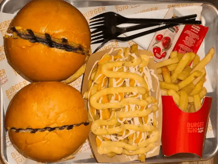 A burger meal with fries and dipping sauces in a fast food style tray.