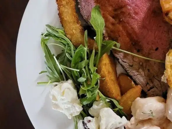 A traditional roast beef platter accompanied by crispy potatoes and creamy coleslaw.