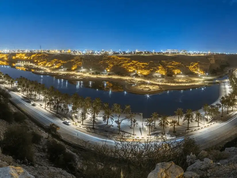 A stunning night view of Wadi Namar, with illuminated hills and water reflections.