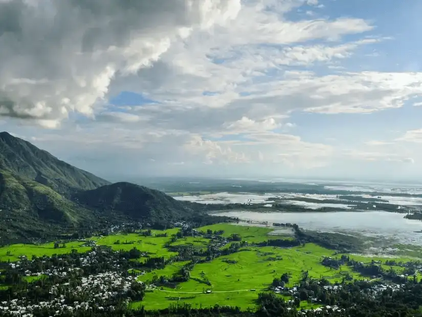 A serene view of Wallar Lake surrounded by green fields and mountains, offering a peaceful atmosphere.