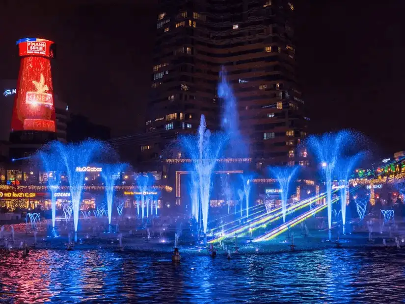 A dazzling evening spectacle of water fountains and lights at a city promenade.