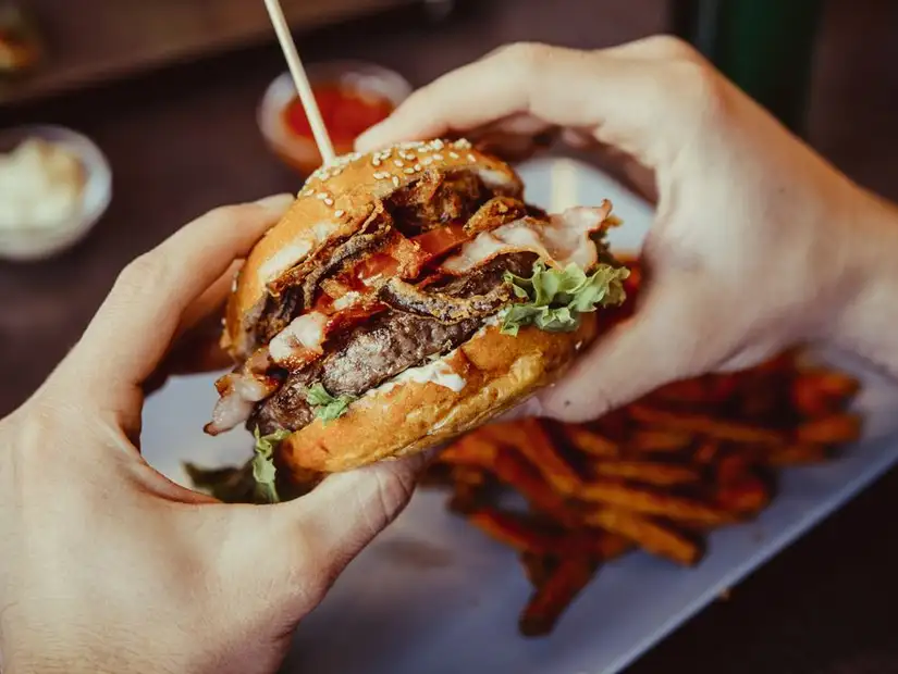 A stacked burger with bacon, cheese, and crispy onions, ready to be devoured.