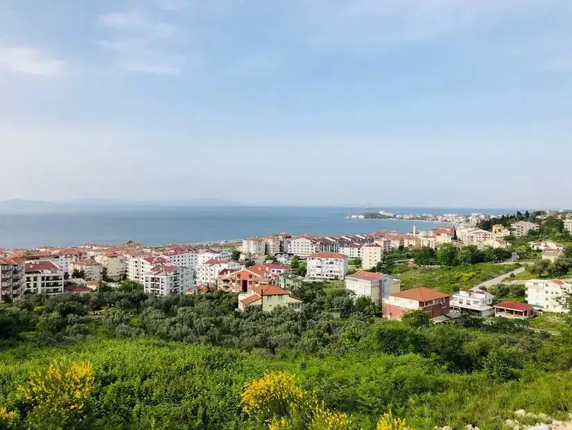 A scenic view of Yalova, with houses along the coastline and green hills in the background.