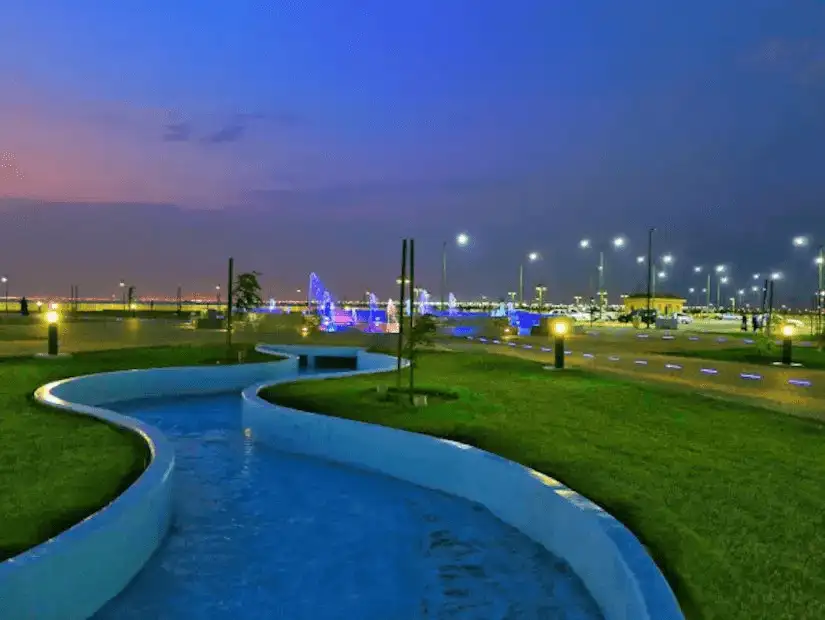 Scenic park at night with illuminated pathways and water features.