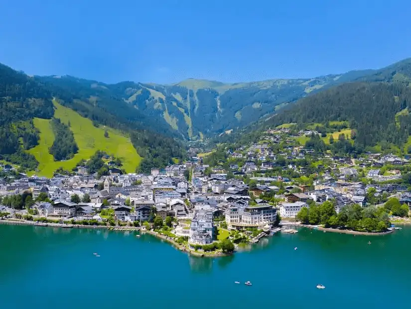 A panoramic view of a beautiful lake with a small town and mountains in the background.