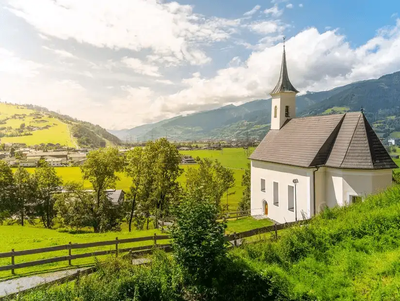 A peaceful countryside scene with a small white church and rolling green hills.